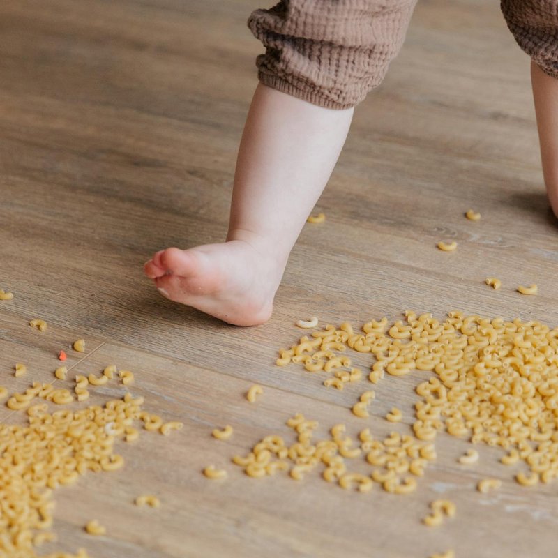 Baby walking on a luxury vinyl floor with spilled food